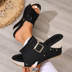Detailed view of women's black wedge sandals featuring golden rivets and a chic buckle accent