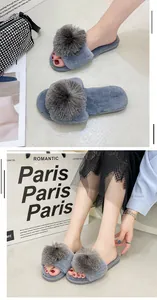 Gros plan sur d'élégants chaussons en fausse fourrure grise avec de grands pompons assortis.