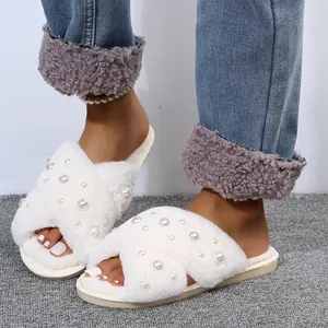 Close-up view of elegant white faux fur slippers with pearl embellishments and cross-bands