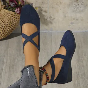 Detailed close-up of navy blue suede wedge flats with elastic cross straps on feet