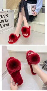 Détail rapproché de pantoufles rouges en peluche ornées d'un grand pompon décoratif élégant.