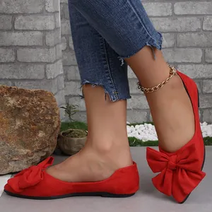 Dettaglio di ballerine scamosciate rosse a punta con elegante fiocco grande