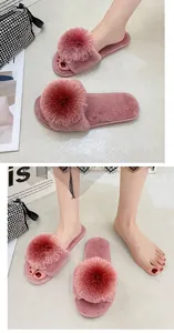Vue détaillée de chaussons en peluche rose pour femmes avec de grands pompons décoratifs