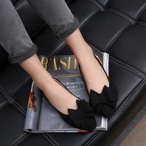 Detail view of black pointed-toe flat shoes with elegant decorative bow on suede upper