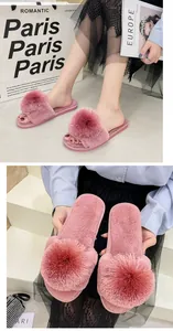 Détail de chaussons ouverts roses à poils avec de grands pompons en fourrure pour femmes