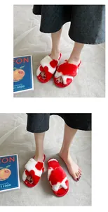 Dettaglio di pantofole da interno in peluche rosse e bianche indossate da un modello.