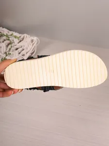 Detailed macro view of the non-slip beige sole and size 39 stamp on black flat sandals