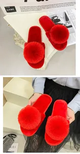 Gros plan de chaussons en peluche rouges avec un grand pompon et texture douce.