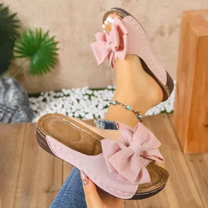 Detailaufnahme der rosa Keilsandaletten mit großer Schleife und Ziernähten