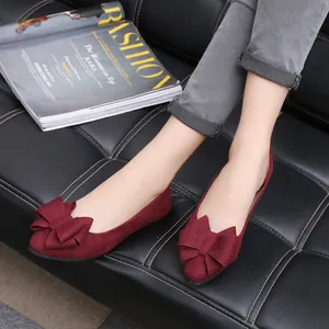 Detailed view of elegant wine red suede pointed-toe flats with a bow decoration on model