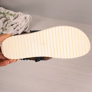 Close-up view showing the non-slip ribbed texture of a black flat beach sandal sole.