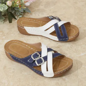 Detail view of casual wedge sandals with navy and white criss-cross straps and buckles.