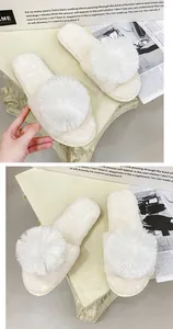 Gros plan de chaussons en fourrure blanche avec un grand pompon décoratif sur la bride.