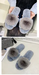 Détail de chaussons en fausse fourrure grise avec grands glands et doublure en peluche