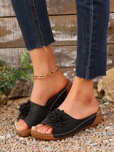 Détail rapproché de sandales compensées noires pour femmes avec fleur 3D et coutures