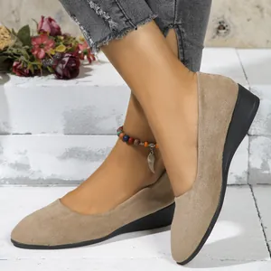 Close-up view of comfortable women's beige suede wedge heel shoes worn with jeans