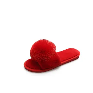 Pantoufles en fausse fourrure rouge à bout ouvert avec un grand pompon décoratif