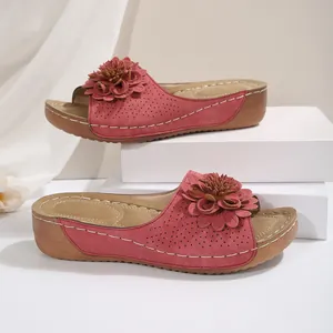 Vue détaillée de mules à talons compensés roses avec fleur 3D et texture perforée