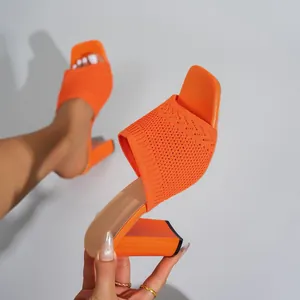 Primo piano di sabot in maglia arancione vivace con un elegante design a punta quadra.
