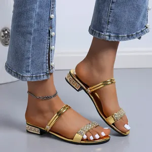 Elegantes sandalias doradas con tiras de pedrería brillante mostradas en los pies.