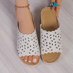 Detail shot of white wedge slippers with intricate floral cutout pattern for summer.