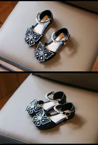 Close-up of girls' black princess sandals with rhinestone butterfly bows and pearls.