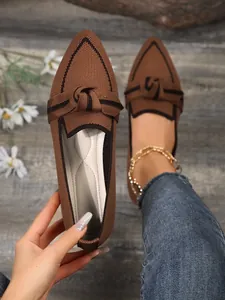 Close-up view of brown breathable fly-knit pointed-toe flat shoes with elegant knot bow detail