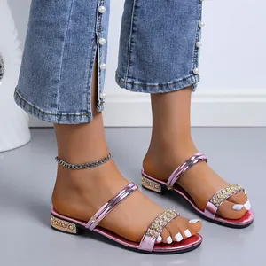 Primer plano de sandalias rosas metalizadas con tiras de pedrería en los pies del modelo