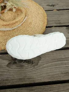 Dettaglio della suola bianca antiscivolo con trama a onde su sandali piatti.