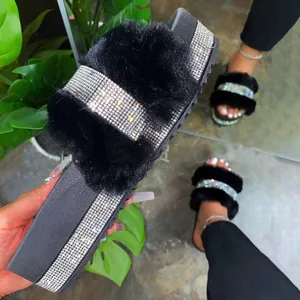 Close-up of black platform slides featuring luxurious faux fur and rhinestone bands.