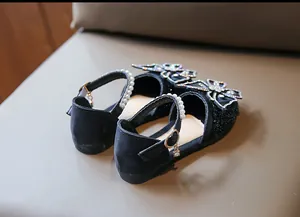 Close-up of elegant black girl's princess shoes with rhinestone bow and pearl strap