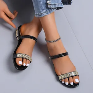 Elegantes sandalias de charol negro con tiras de pedrería brillante y tacón medio.