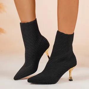 Detailaufnahme von schwarzen Strick-Stiefeletten mit spitzen Zehen und goldenen Pfennigabsätzen.