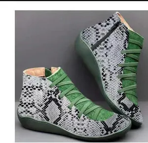 Detailed view of women's flat ankle boots with green and snakeskin print texture