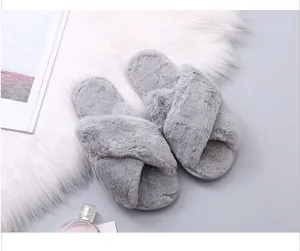 Close-up of soft grey faux fur cross-strap slippers on a white plush rug for cozy home vibes