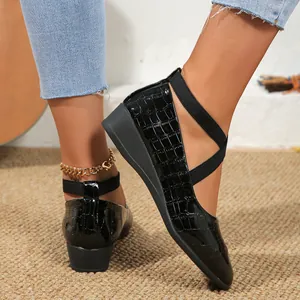 Detailed close-up of black crocodile pattern wedge pumps with cross elastic straps