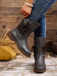 Nahaufnahme stilvoller grauer Damen-Stiefeletten mit Schnürung, Nietenbesatz und rustikalem Vibe.