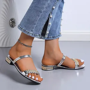 Primer plano de elegantes sandalias plateadas con pedrería y tacones bajos para mujer