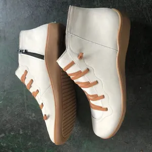 Close-up detail view of beige women's flat Martin boots with brown laces and side zipper