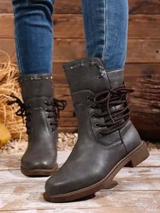 Nahaufnahme grauer Damen-Stiefeletten mit dekorativen Nieten und seitlicher Schnürung