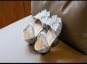 Detailed view of silver glittery girl's princess shoes with rhinestone bow knots