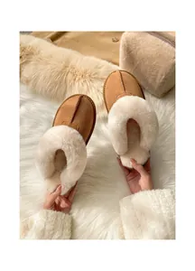 Macro view of tan suede slippers with plush cream faux fur lining for winter comfort.