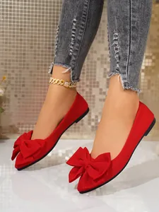 Close-up view of elegant red pointed-toe ballet flats with a large bow detail