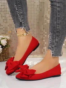 Close-up of elegant red square toe ballet flats featuring large decorative bows on feet