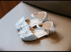 Close-up of silver glitter girls' princess shoes with large pearl butterfly ornament.