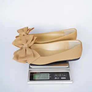 Beige fabric bow-knot flat shoes for women weighing 218 grams on a silver digital scale.