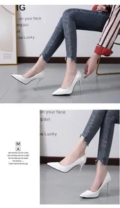 Detail view of elegant white pointed-toe stiletto high heels worn by a fashion model