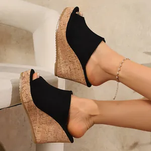 Close-up of black suede wedge sandals with cork platform and fish mouth design.
