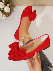 Close-up of red flat women's shoes with large decorative bow on square toe
