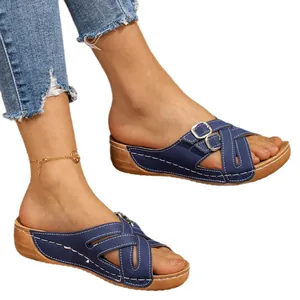 Navy blue wedge sandals with white stitching and decorative double buckles on model